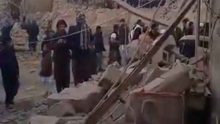 People gather near rubble in the aftermath of Pakistan's strike on an Iranian village near Saravan, Sistan and Baluchistan Province,